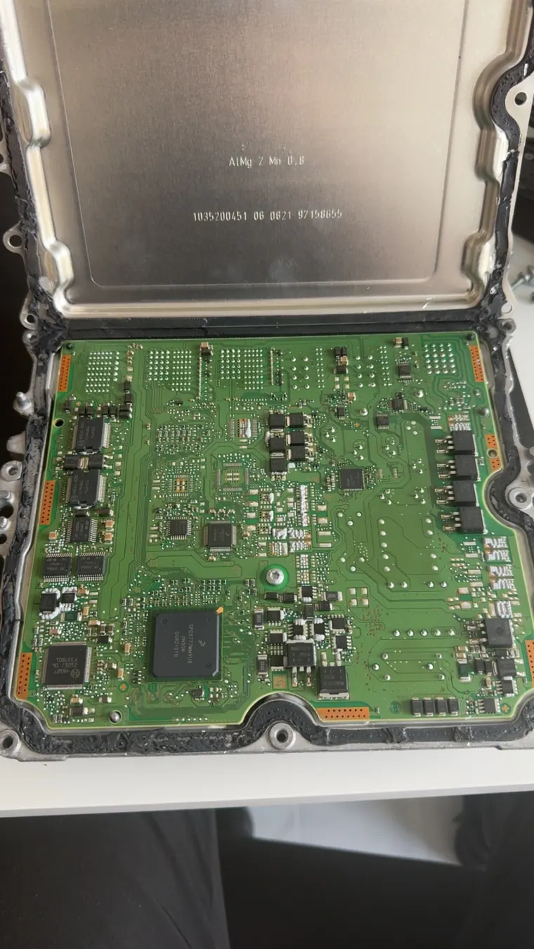 Opened engine control unit showing its internal circuit board and electronic components